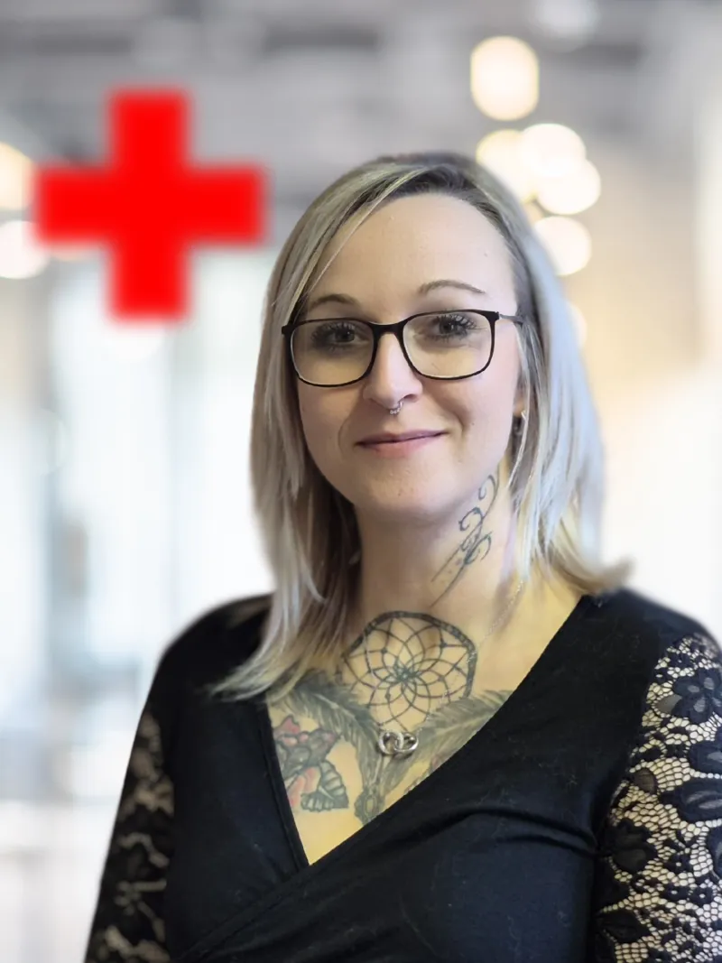 Eine Junge Frau mit aschblonden haaren, einer brille die in die Kamera schaut